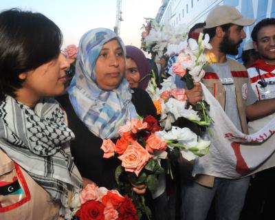 Personnes tenant des fleurs et des drapeaux devant le navire turc, en attendant de réceptionner les blessés et malades qui seront soignés dans le pays.